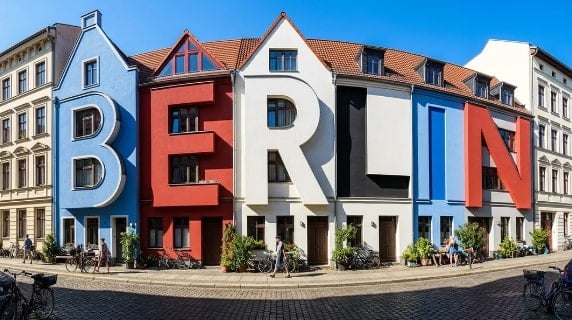 Häuser ergänzt durch die Buchstaben BERLIN in den Farben Blau und Rot sowie Weiß und Schwarz