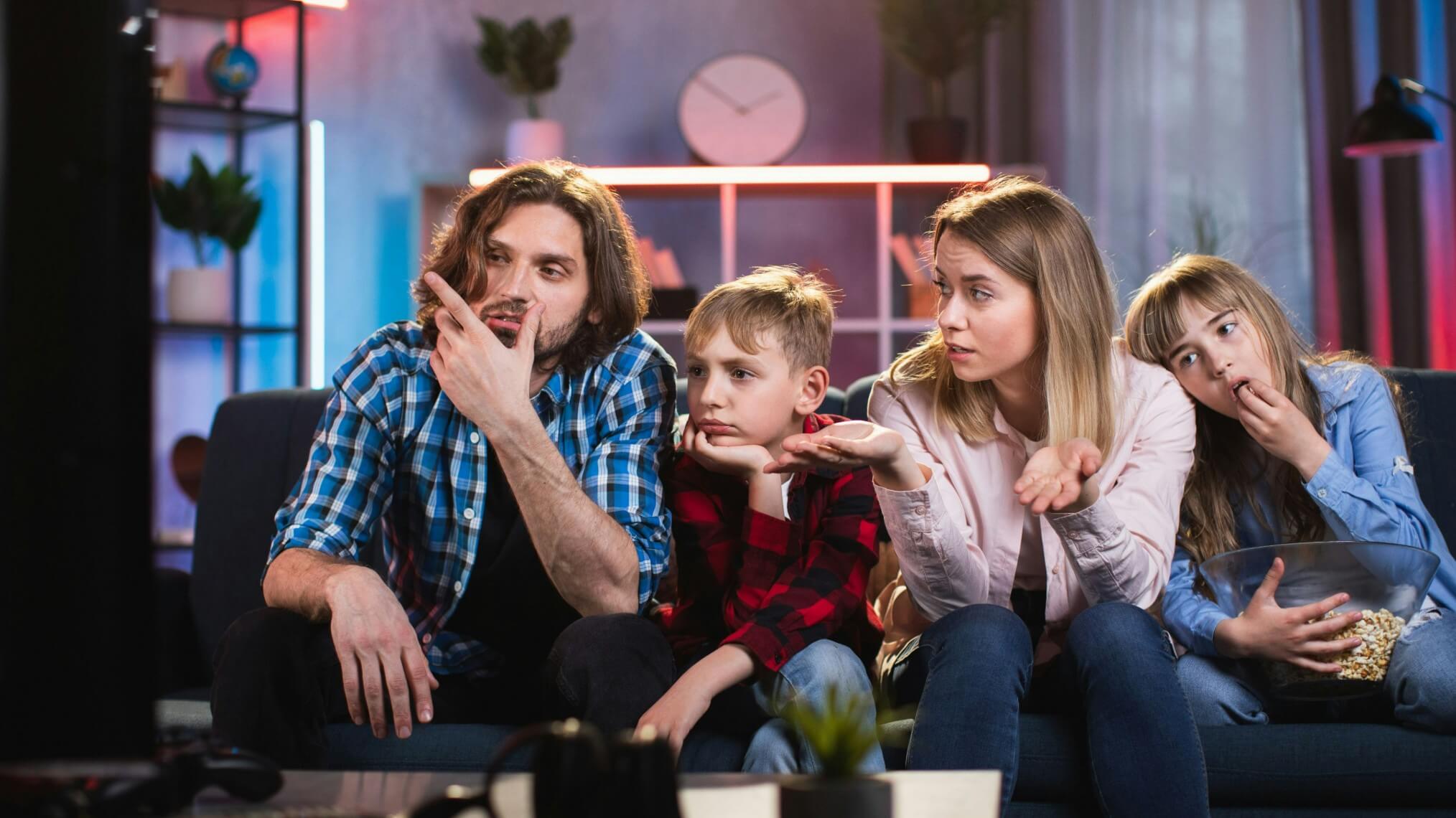 Faça um trailer para uma série familiar com uma família de quatro pessoas sentada no sofá assistindo TV