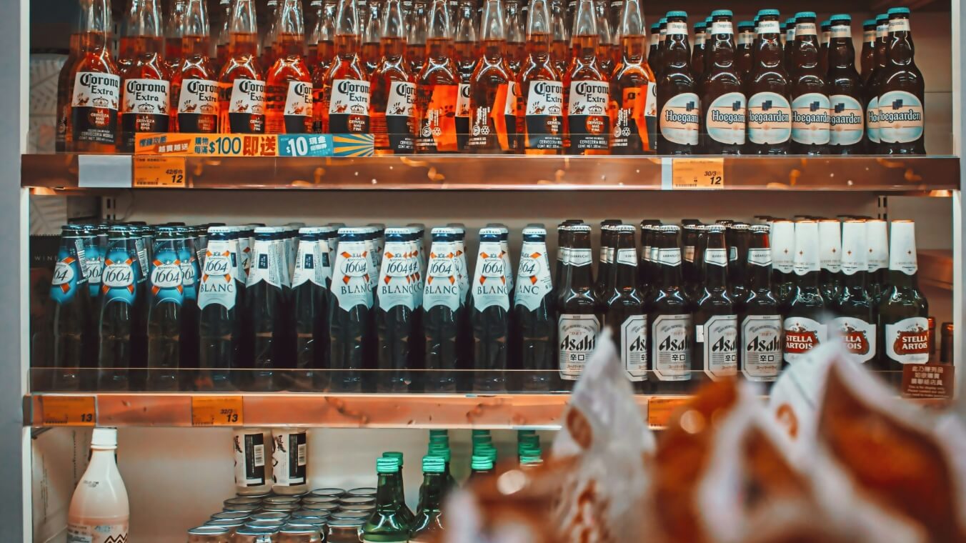 diferentes tipos de bebidas alcoólicas estão exibidos ordenadamente na vitrine